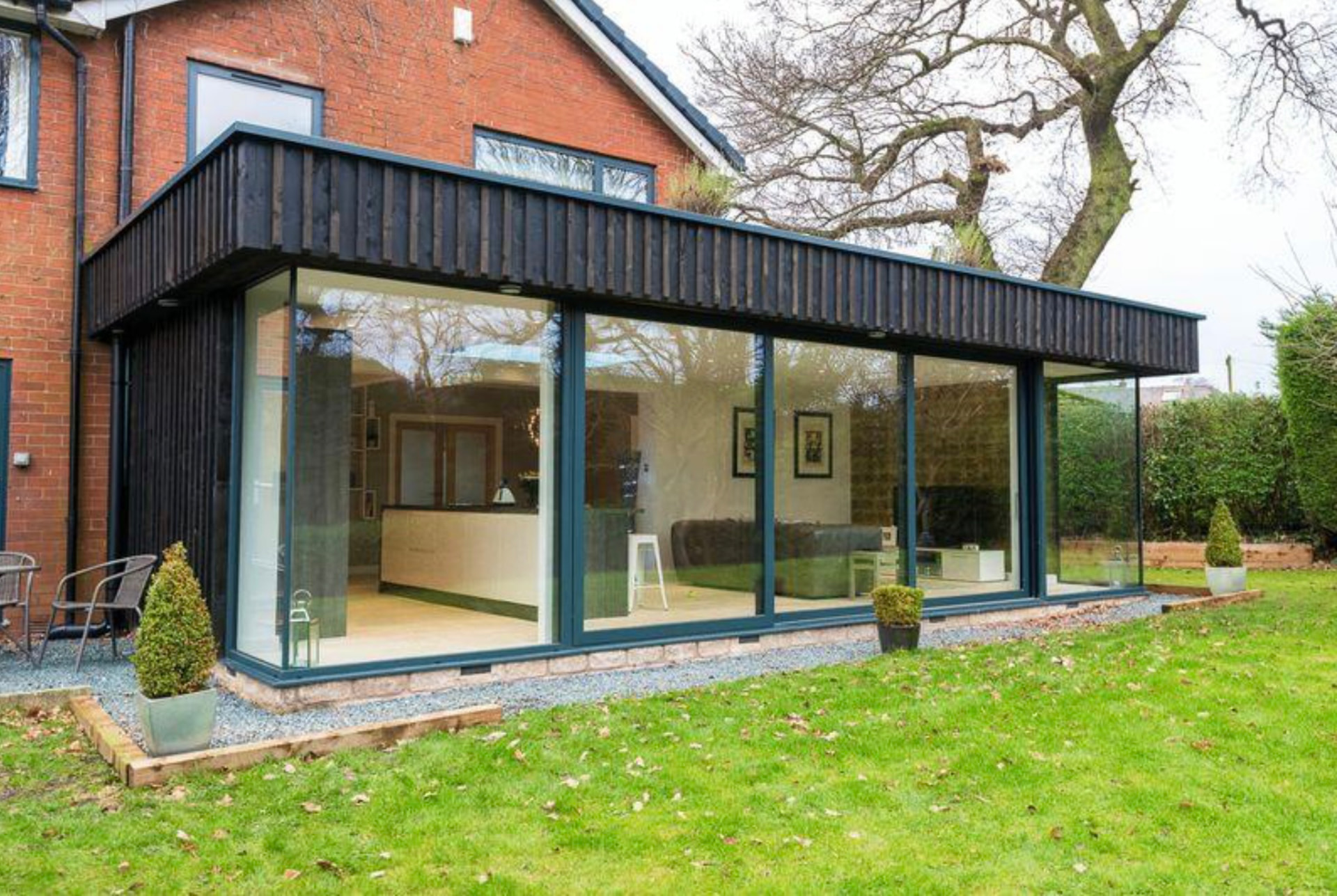 Glass-to-glass corner extension with sliding doors framing a garden view